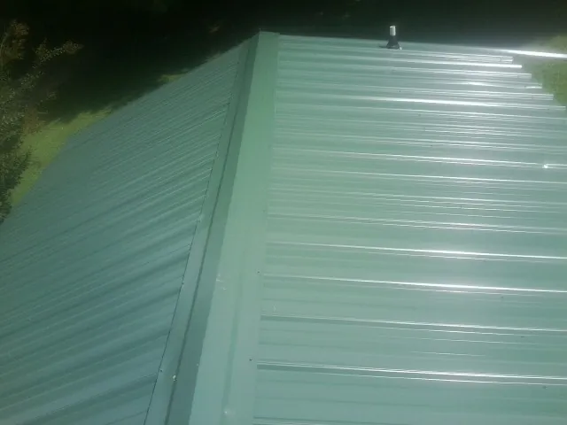 New green metal panels meeting at the ridge of a roof — Flat Roof Repair work by our crew in Edgar