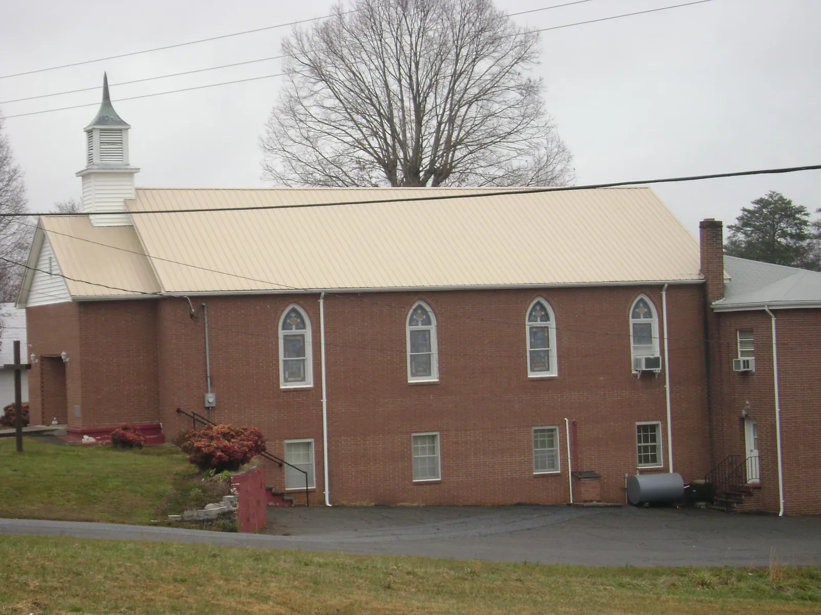 New tan metal roof on a brick church with a white steeple in Edgar